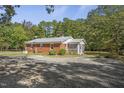 Back view of home with large gravel parking area and mature trees at 6418 Beaver Creek Rd, New Hill, NC 27562