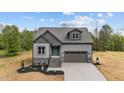 Charming new construction home featuring stone accents, a two-car garage, and a welcoming teal front door at 65 Leisure Ln # 6, Louisburg, NC 27549