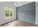 Bright room featuring an accent wall, a modern chandelier, and a large window that provides ample natural light at 65 Leisure Ln # 6, Louisburg, NC 27549
