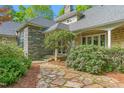 Charming home exterior with stone accents, shingle siding, a stone walkway and mature flowering bushes at 6600 Maynard Farm Rd, Chapel Hill, NC 27516