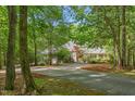 Secluded home exterior featuring lush landscaping, a circular driveway, and a mix of stone and shingle siding at 6600 Maynard Farm Rd, Chapel Hill, NC 27516