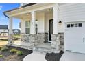 Inviting front porch with stone-covered columns and a seating area for relaxing outdoors at 67 Comfort Ct, Fuquay Varina, NC 27526
