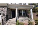 Inviting front porch with stone accents, black railings, and white columns at 705 Blue Pointe Path, Apex, NC 27523