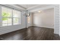 Sunlit dining area featuring a modern chandelier, large window, and dark hardwood floors at 7104 Rex Rd, Holly Springs, NC 27540