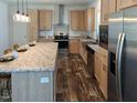 Modern kitchen boasts stainless appliances, granite countertops, wooden cabinetry, and pendant lighting at 765 Whitley Rd, Middlesex, NC 27557