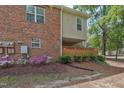 View of the side of the townhouse, showcasing brickwork and vibrant landscaping with flowering bushes at 497 Summerwalk Cir # 497, Chapel Hill, NC 27517
