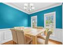 Bright dining room boasts wainscoting, chandelier lighting, and light wood table with seating for six at 11 Glen Valley Ct, Angier, NC 27501