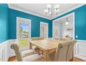 Dining room with turquoise walls features wainscoting, chandelier, and light wood table with six chairs at 11 Glen Valley Ct, Angier, NC 27501
