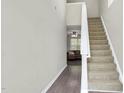 View of hallway with wood-look floors, neutral wall paint, carpeted staircase and living room beyond at 136 River Pearl St, Raleigh, NC 27603
