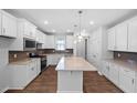 Bright, spacious kitchen with white cabinets, island, stainless appliances, and designer lighting at 2328 Beeblossom Pl, Fuquay Varina, NC 27526