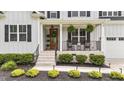 Inviting front porch with rocking chairs, hanging plants, and manicured landscaping leading to the front door at 257 Reese Dr, Willow Springs, NC 27592