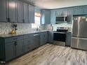 Well-equipped kitchen featuring gray cabinets, stainless steel appliances, and stunning backsplash, and wood-look floors at 307 S Smithfield Rd, Knightdale, NC 27545