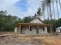 New home under construction featuring a covered porch, surrounded by tall trees and construction materials at 329 Green Pines Estates Dr, Kenly, NC 27542
