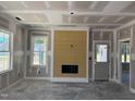 Living room featuring fireplace with yellow accent wall, white trim, and natural light from double hung windows at 329 Green Pines Estates Dr, Kenly, NC 27542