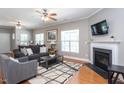 Cozy living room featuring a fireplace, ceiling fans, and large windows that flood the space with natural light at 3827 Heritage Spring Circle Cir, Wake Forest, NC 27587