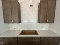 Close up shot of a kitchen with wood cabinets, quartz countertops, and tile backsplash at 40 Wabash St, Pittsboro, NC 27312