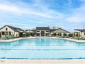 A luxurious pool with a tanning ledge featuring blue lounge chairs and umbrellas, surrounded by elegant clubhouse buildings at 40 Wabash St, Pittsboro, NC 27312