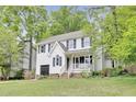 Two-story home with a garage, a front porch swing, mature trees and landscaped front yard at 4711 Buttonbush Dr, Durham, NC 27712