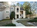 Exterior view of a multi-story tan condo with green trees, landscaping, and sidewalks at 6011 Winterpointe Ln # 205, Raleigh, NC 27606