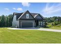 View of a craftsman style house with black trim, a two-car garage and surrounding green lawns at 8629 Dukes Lake Rd, Zebulon, NC 27597