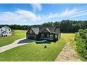 Aerial view of a craftsman style house with black trim and green lawns in a quiet area at 8629 Dukes Lake Rd, Zebulon, NC 27597