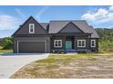 Contemporary home with a teal front door, dark gray siding, black garage door, and well-manicured lawn at 8629 Dukes Lake Rd, Zebulon, NC 27597