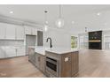 Open-concept kitchen featuring an island with a sink, stainless steel appliances, and a cozy fireplace in the living area at 9305 Field Maple Ct, Raleigh, NC 27613