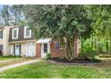 View of the townhouse with a manicured lawn and a mature tree in the front yard at 13 Patriot Cir, Durham, NC 27704