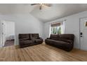 Spacious living room featuring beautiful hardwood floors, natural light, and comfortable brown sofas at 14 Shire Ct, Zebulon, NC 27597