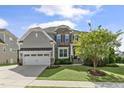 Beautiful home featuring stone accents, a two-car garage, manicured lawn and mature tree at 1429 Wragby Ln, Apex, NC 27502