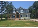 Charming two-story home featuring a covered porch, lush lawn, and a mix of modern and classic design elements at 15 Independence Dr, Smithfield, NC 27577