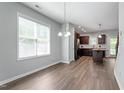Open dining area with wood floors, large windows, and view into the kitchen with dark wood cabinets at 162 W Lumber Ct, Clayton, NC 27520