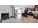 Open-concept living space featuring wood floors, fireplace, staircase, and kitchen with island and black appliances at 162 W Lumber Ct, Clayton, NC 27520