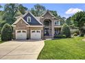 Charming brick two-story home featuring a three-car garage, manicured lawn, and lush trees at 2637 Forestbluff Dr, Fuquay Varina, NC 27526