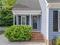 Cozy side entrance with brick steps, black door, and lush green shrubbery at 2908 Bolo Trl, Raleigh, NC 27615