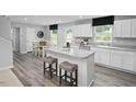 Bright kitchen features an island with seating, white cabinets, and stainless steel appliances at 294 N Coral Bells Way, Four Oaks, NC 27524