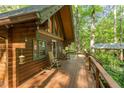 Inviting deck with rocking chairs on a wood cabin with wooden siding and lush surroundings at 300 Rabbit Run, Pittsboro, NC 27312