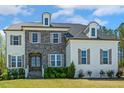 Charming two-story home featuring a mix of stone and painted brick and a well-manicured lawn at 304 Channel Cove Dr, Holly Springs, NC 27540
