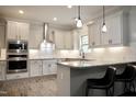 Modern kitchen featuring white cabinets, granite countertops, stainless steel appliances, and stylish pendant lighting at 335 Gwendolyn Way, Fuquay Varina, NC 27526