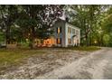 A charming two-story home, nestled among mature trees, features a welcoming porch and a tranquil setting at 3521 Banks Rd, Raleigh, NC 27603