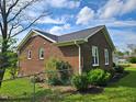 Side view of a brick home with white framed windows and a well-maintained lawn surrounded by a chain link fence at 3785 Little Creek Church Rd, Clayton, NC 27520