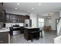 Modern kitchen with stainless steel appliances, dark cabinets, and island with breakfast bar at 39 Principal Way, Clayton, NC 27520