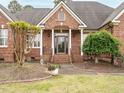 Inviting front entrance featuring a brick facade, decorative columns, and manicured landscaping at 4501 Forest Dr, Holly Springs, NC 27540
