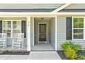 Inviting covered entryway with rocking chairs and a 'WELCOME' sign, framed by dark shutters and light siding at 479 Kotata Ave, Bunnlevel, NC 28323