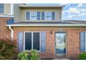 Close up of brick townhome showing light landscaping and matching blue shutters on the windows at 48 Fashion Pl, Durham, NC 27705