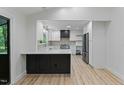 Open-concept kitchen features white cabinets, stainless steel appliances, a modern island, and wood-look floors at 6421 Arrington Rd, Raleigh, NC 27607