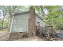 View of the side of the house with a brick chimney and wood staircase leading to a second entryway at 7312 Ray Rd, Raleigh, NC 27613