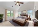 Spacious main bedroom with a vaulted ceiling, ceiling fan, carpeted floor, and multiple windows at 7851 Allscott Way, Raleigh, NC 27612