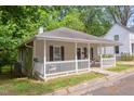 Charming home featuring a cozy front porch, neutral siding, dark shutters, and mature landscaping at 919 Orient St, Durham, NC 27701