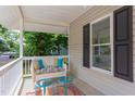 Relaxing front porch seating area with wicker sofa, blue tables, and a colorful outdoor rug at 919 Orient St, Durham, NC 27701
